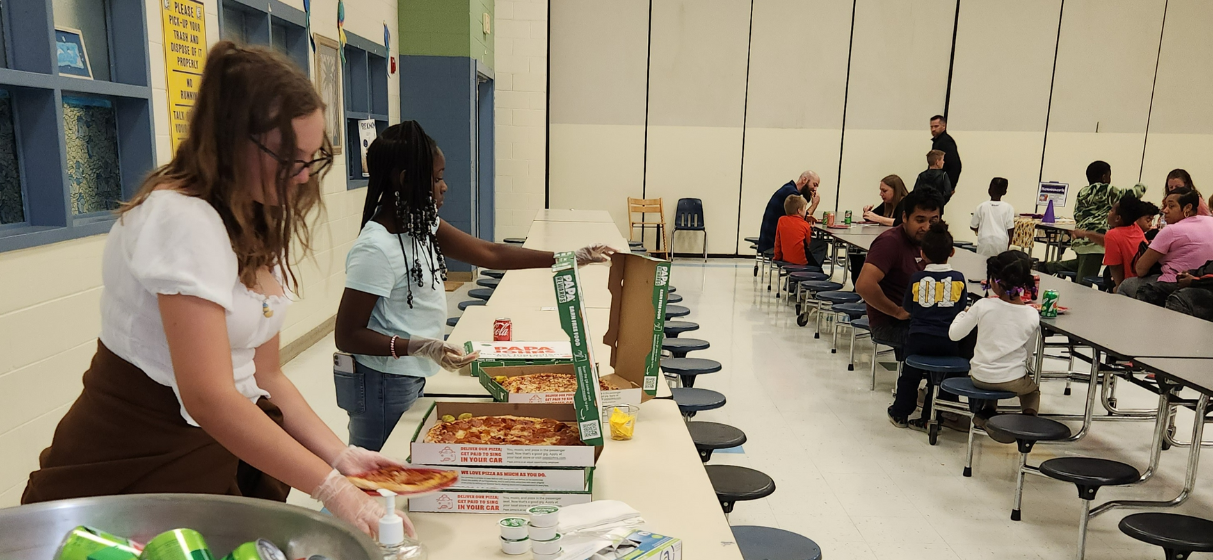  Staff, students, and guardians attending curriculum night in cafeteria. 